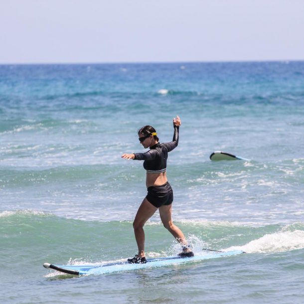 Women standing on a surfboard and catching a small wave in Encuentro Beach, during the Kite Sisters Women Kiteboarding Camp in Cabarete, Dominican Republic