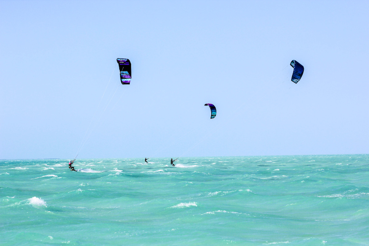 A group of 4 female Kitesurfers riding in Belize Kitesurf spot, an open turquoise water sandbar