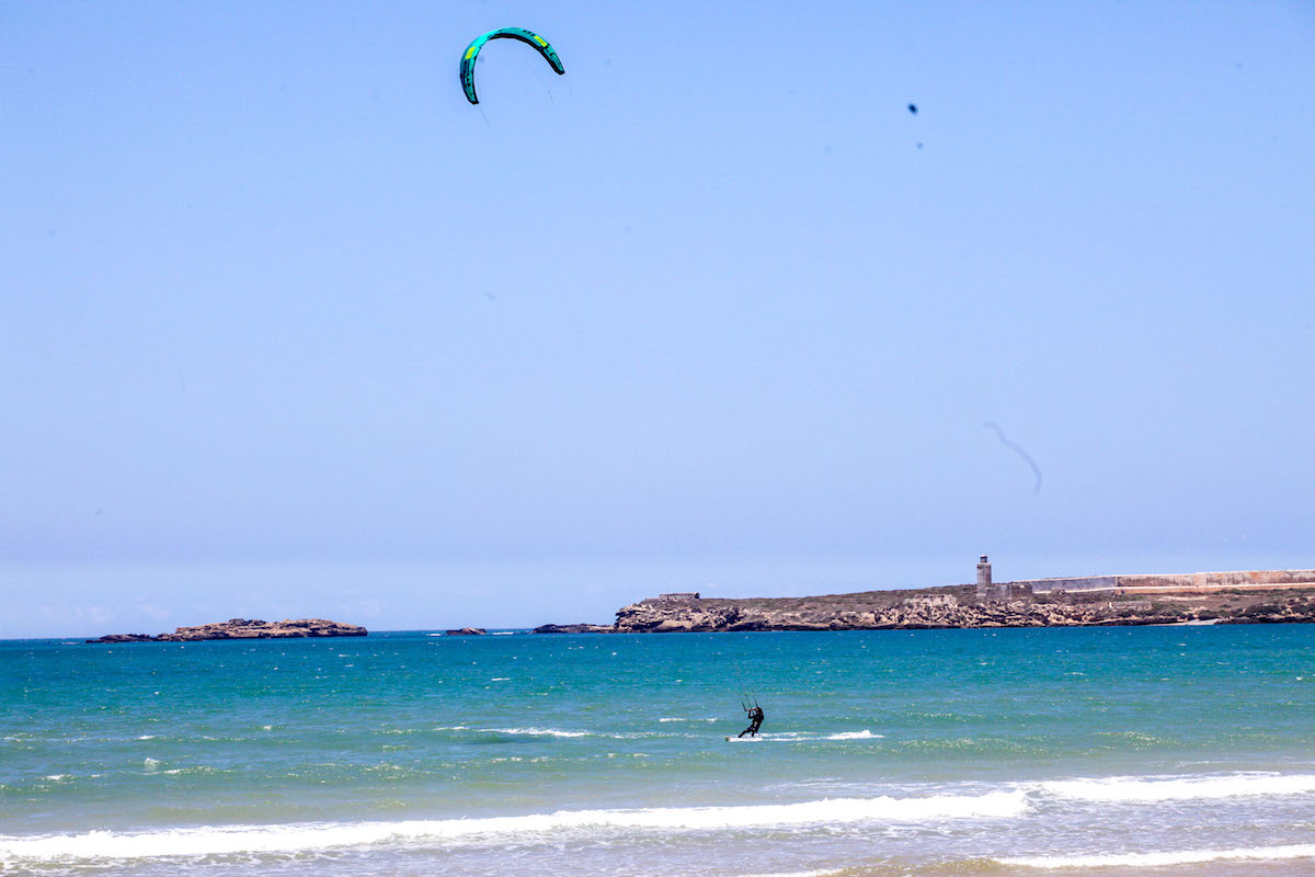 A view of Kitesurf Essaouira Morocco beach: an open blue ocean, with small chop and a kiter enjoying her time in the water
