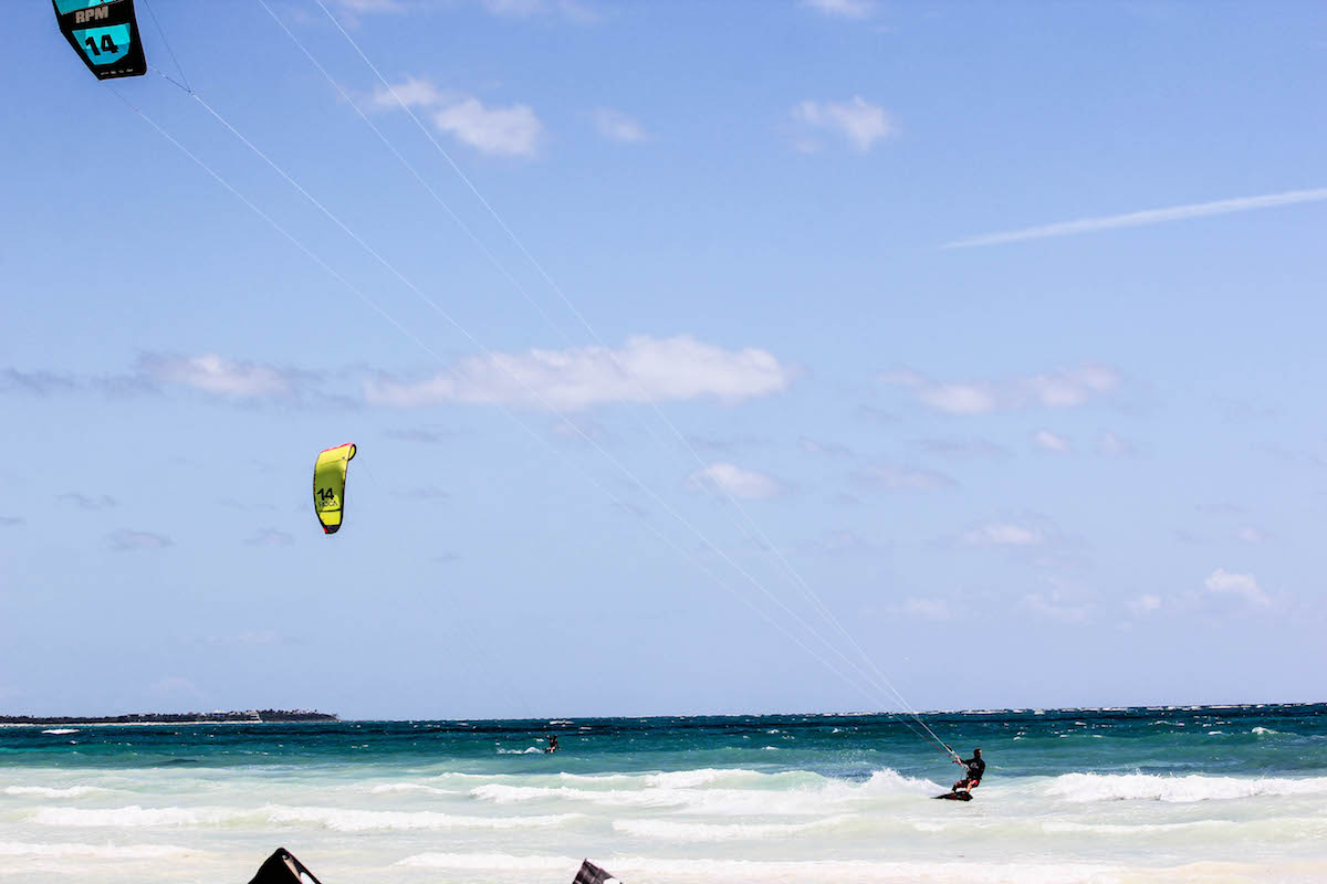 A stunning beach with white sand, turquoise water and 2 kitesurfers enjoying the conditions